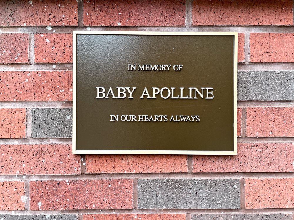 A plaque that says "In memory of Baby Apolline in our hearts always"