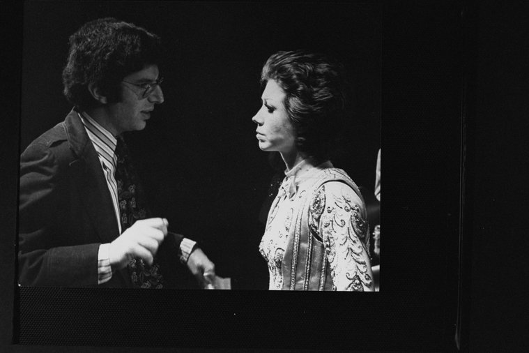 A black and white photo of a man talking to a woman.
