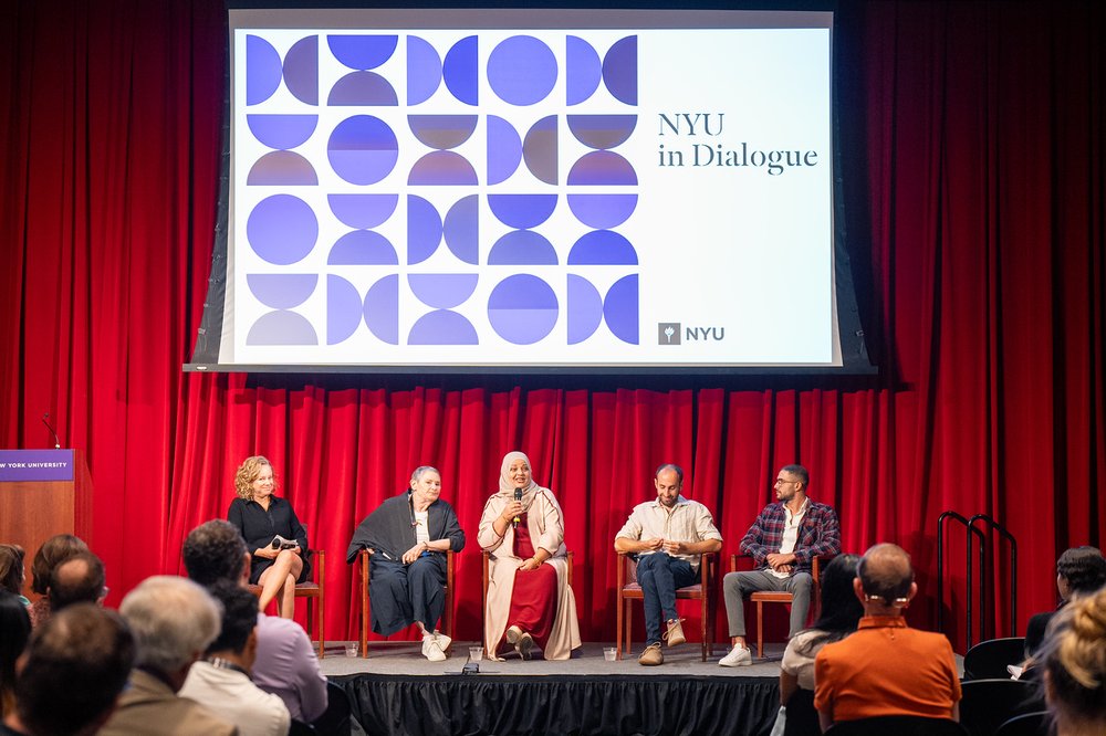 Speakers onstage at an event with "NYU in dialogue" on a screen in the background.