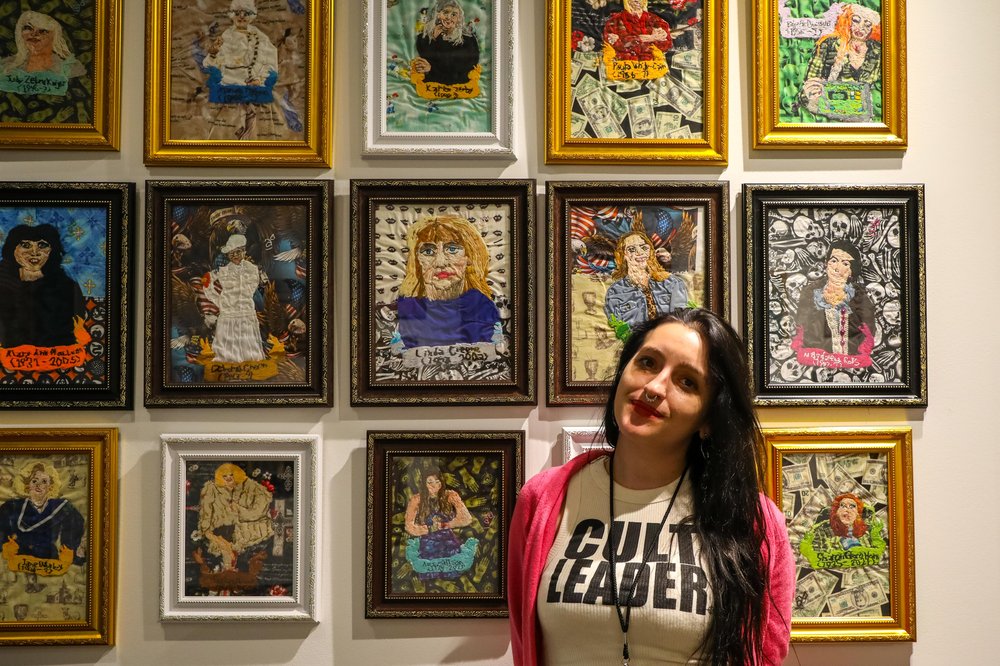 outsider-18.jpg A woman stands in front of paintings.