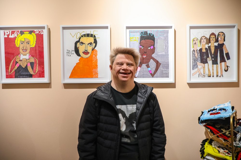 outsider-3.jpg A man stands in front of his paintings