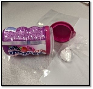 A Mentos gum container with what appears to be bags of drugs next to it.