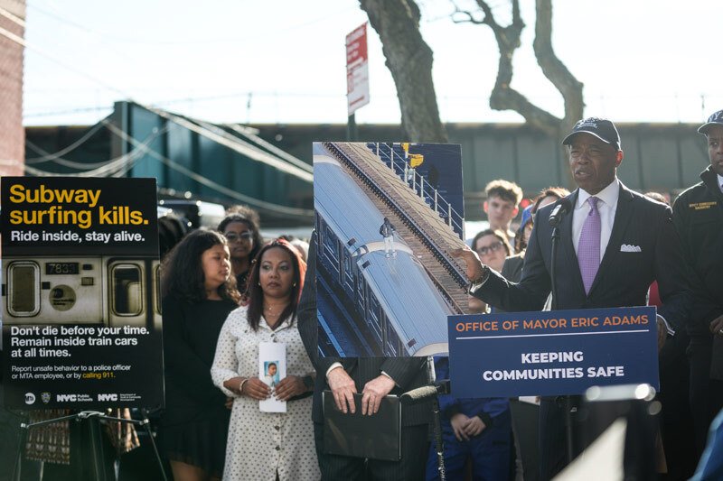 Norma Nazario, second from left, front row, stands at a press conference in October 2024 as Mayor Eric Adams holds a photo of an unidentified individual subway surfing.