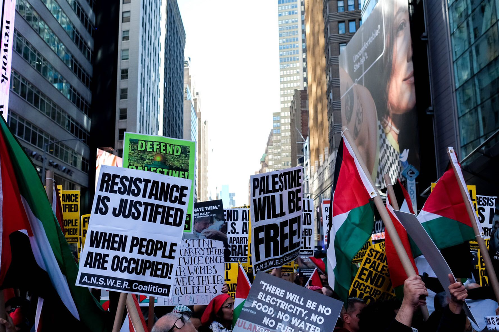 Protesters in Times Square with signs reading "Resistance is justified when people are occupied" and "Palestine will be free"