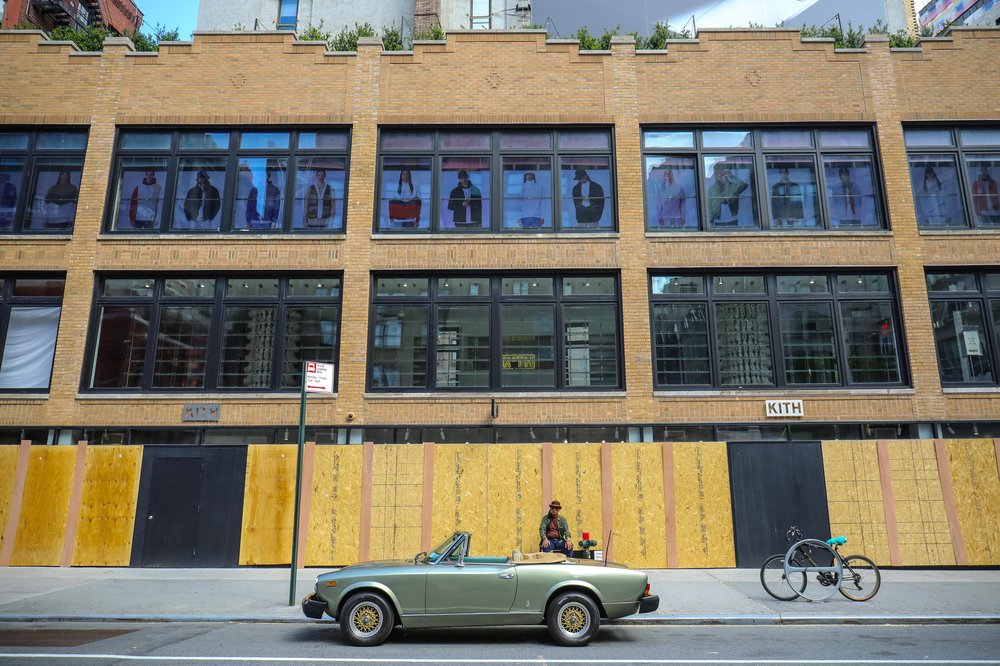 A boarded up store, with old car parked in front