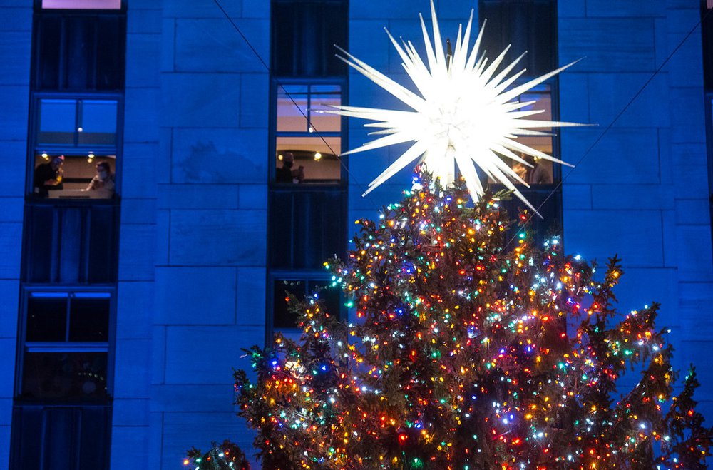 A close up of the top of the tree; people inside 30 Rock can be see in the windows taking pictures
