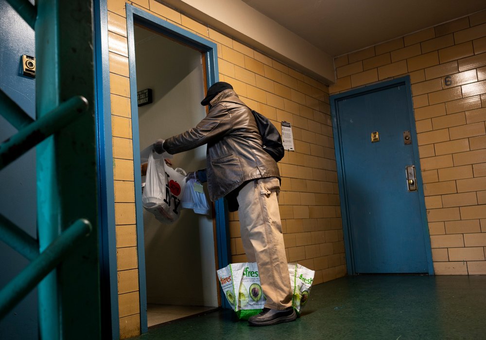 Victor Coles delivers a meal from the food distribution by the organization Urban Upbound, to an elderly woman at the Queensbridge Housing complex on April 16th, 2020.
