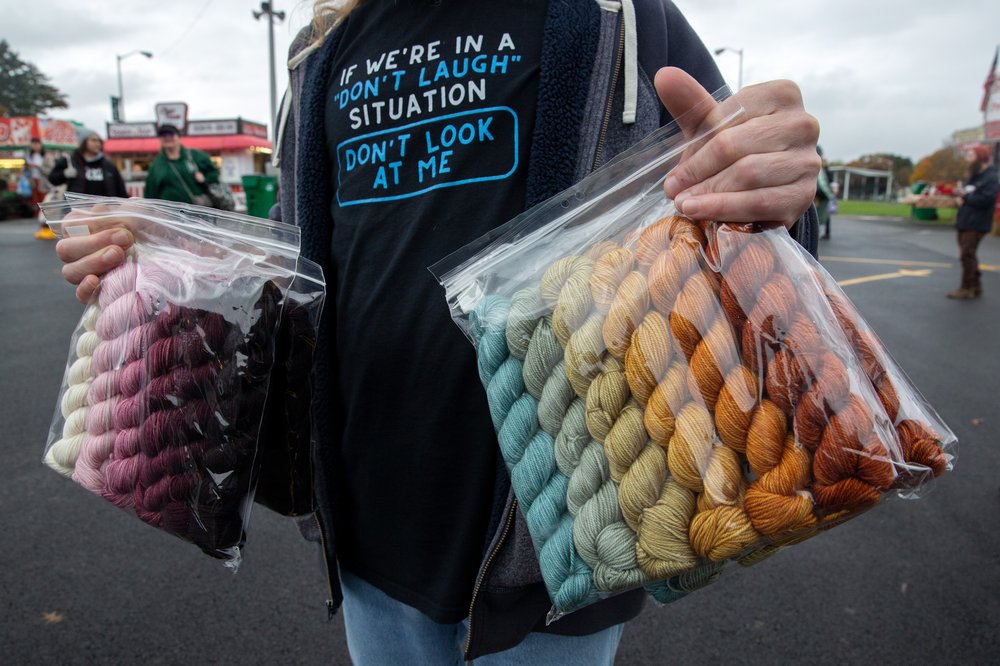 A person holding colorful bags of yarn.