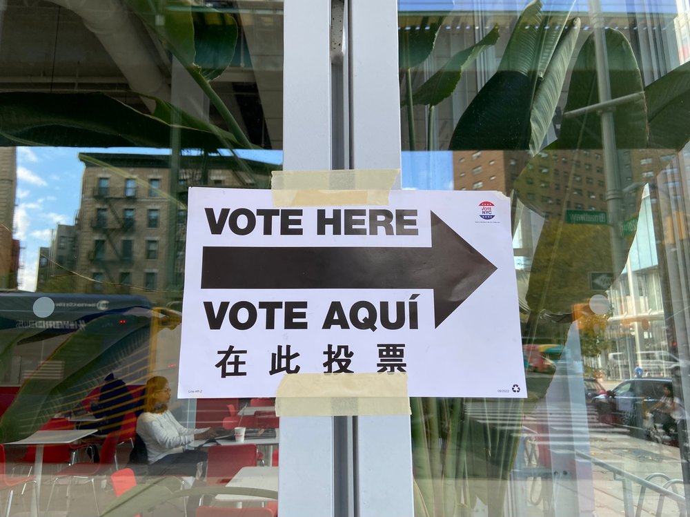 A Vote Here Vote Aqui voting sign in English, Spanish and Chinese taped to a building with a polling site in New York City.