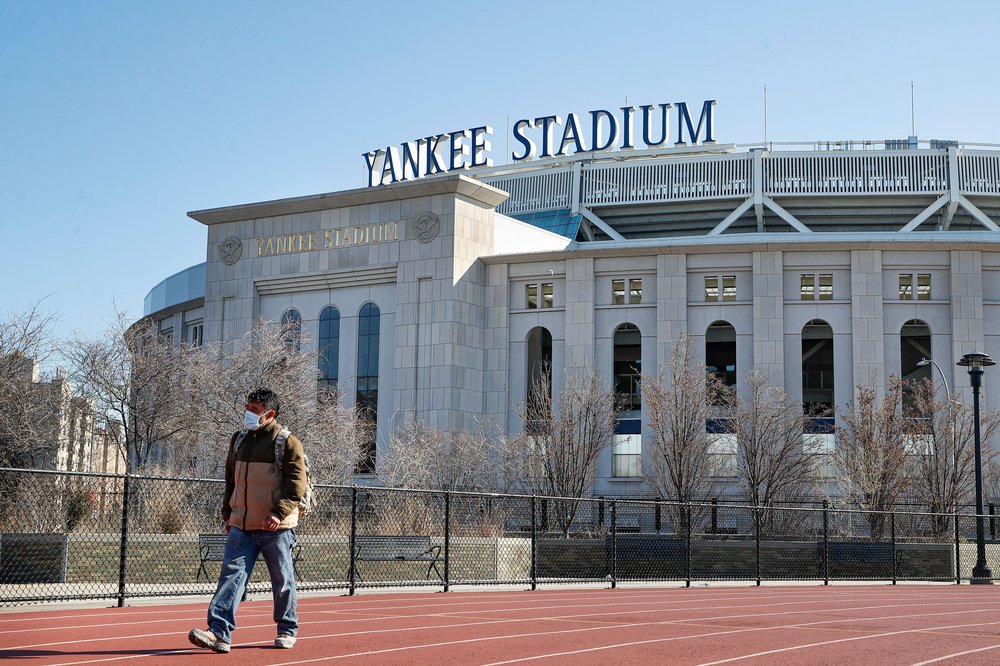 Pedestrian walks a running track while wearing a surgical mask near Yankee Stadium as it remains closed due to COVID-19 concerns, in the Bronx borough of New York.