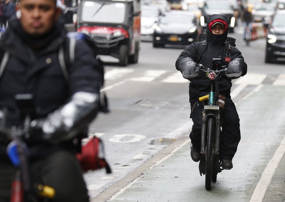 Delivery workers ride bikes down Seventh Avenue in Times Square.
