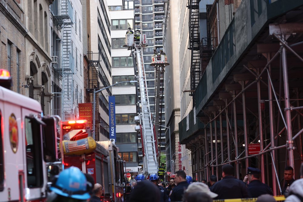 New York City Fire Department firefighters work on ladder trucks at the scene of a parking structure collapse in the Financial District of New York City, New York, USA, 18 April 2023. Fire Department officials have reported three injuries but advised they expect that to increase.