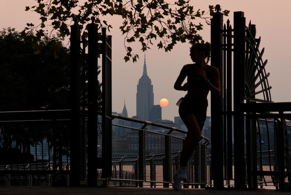 a woman jogging in Central Park during a smoky sunrise