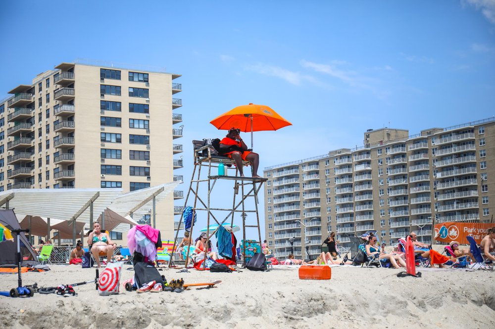 A lifeguard sits in a lifeguard stand on the beach