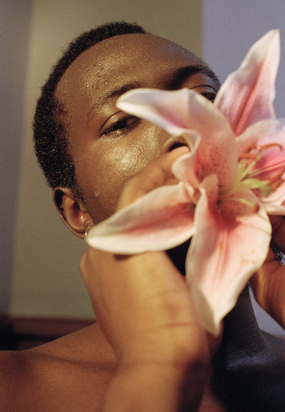 A photograph of a man looking at a flower.