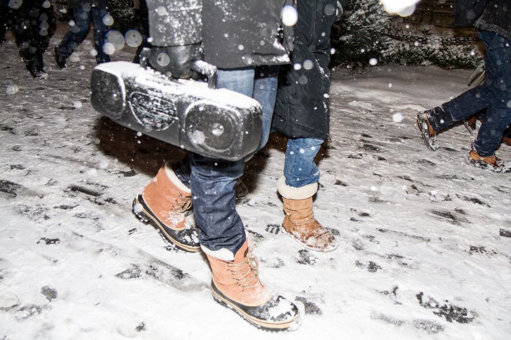 A person clutches a music player in their hand on a snowy night.