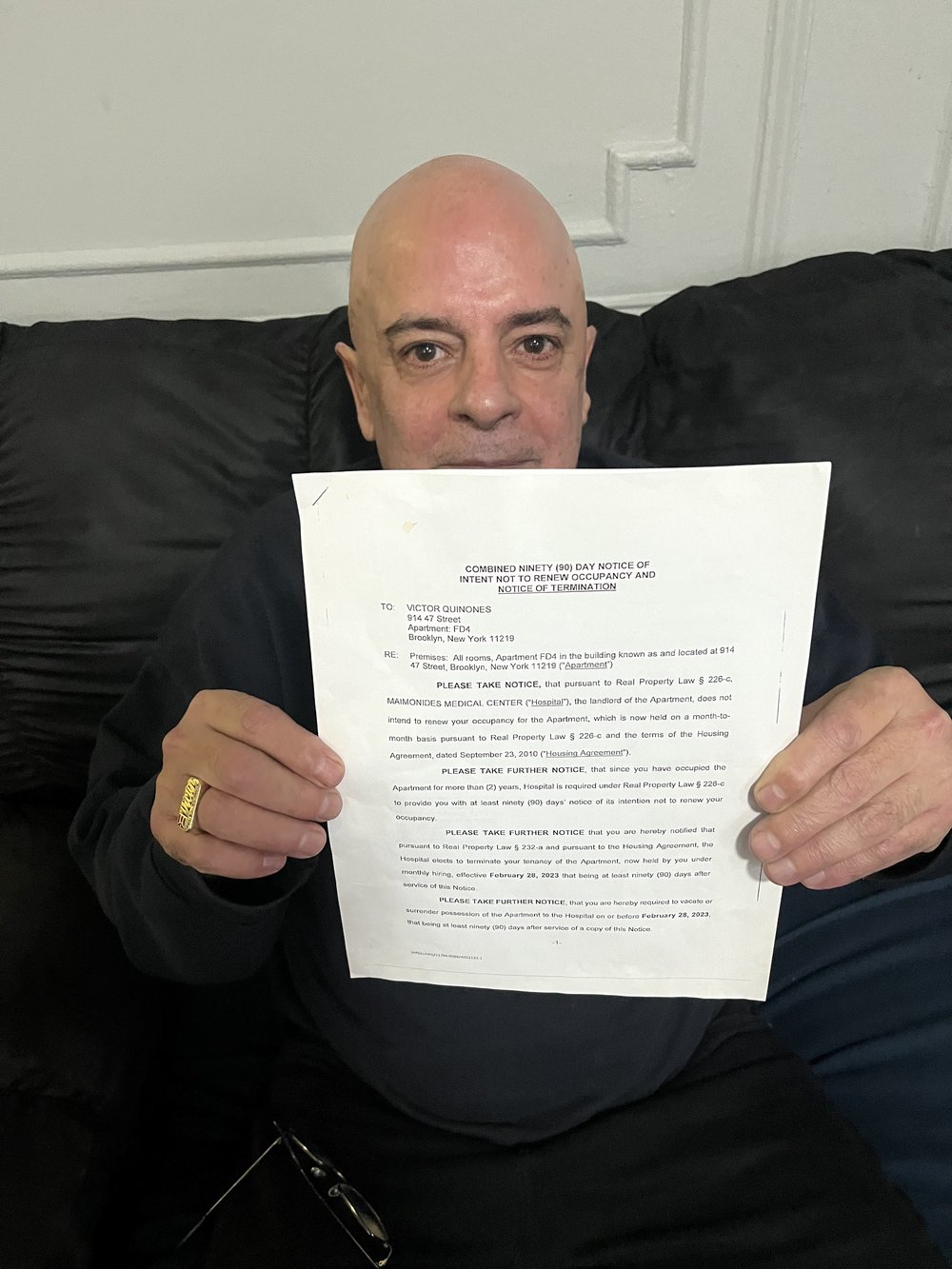 Victor Quiñones, 66, holds up the notice he received in November 2022 giving him 90 days to vacate his apartment. He is one of approximately three dozen current and former Maimonides employees who are being evicted from their apartments by the hospital.