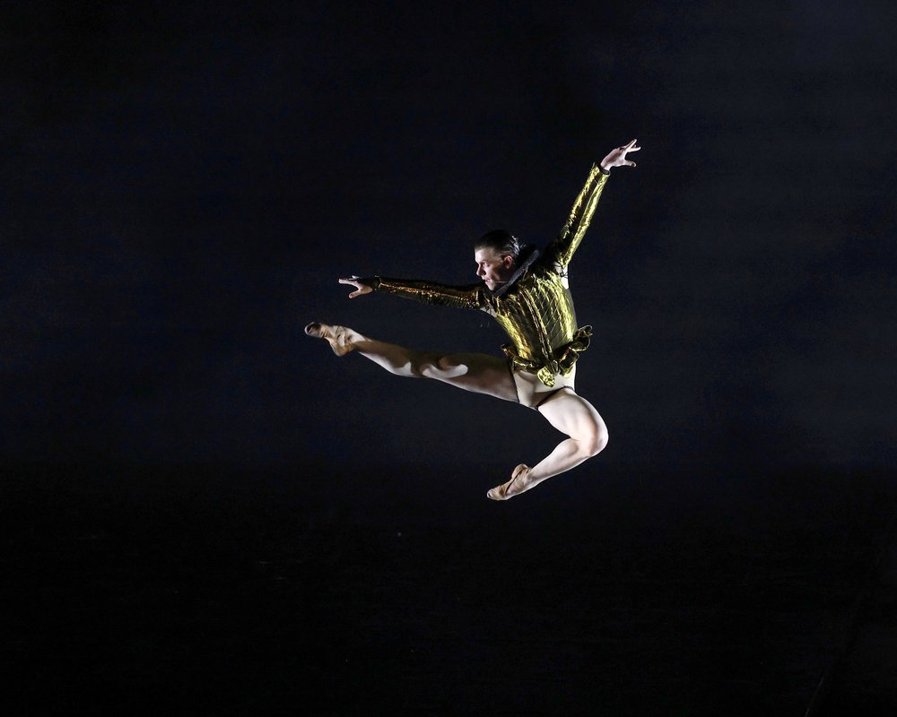 A man in a green outfit leaps