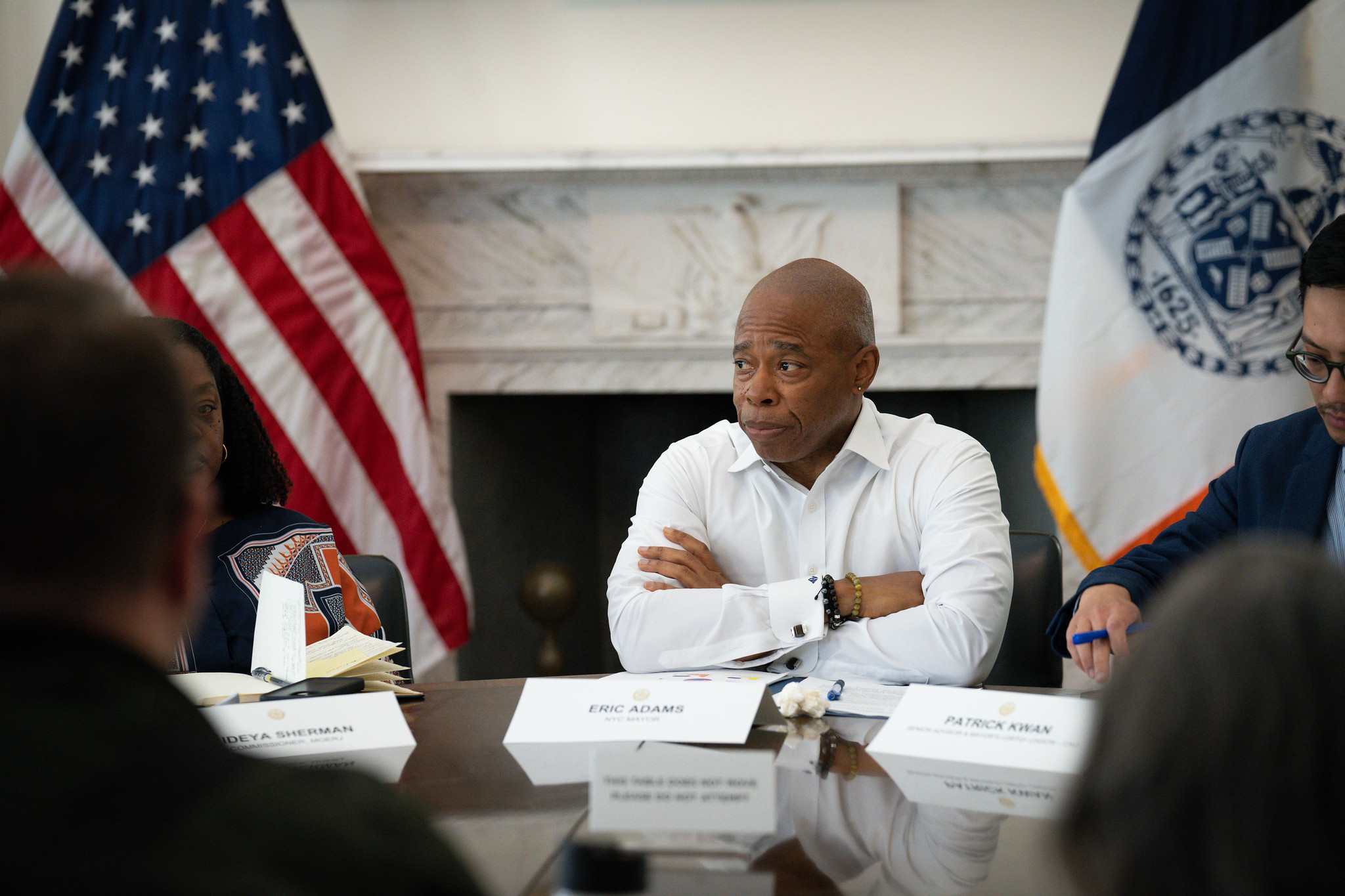 Mayor Eric Adams sits at a table with his arms crossed.