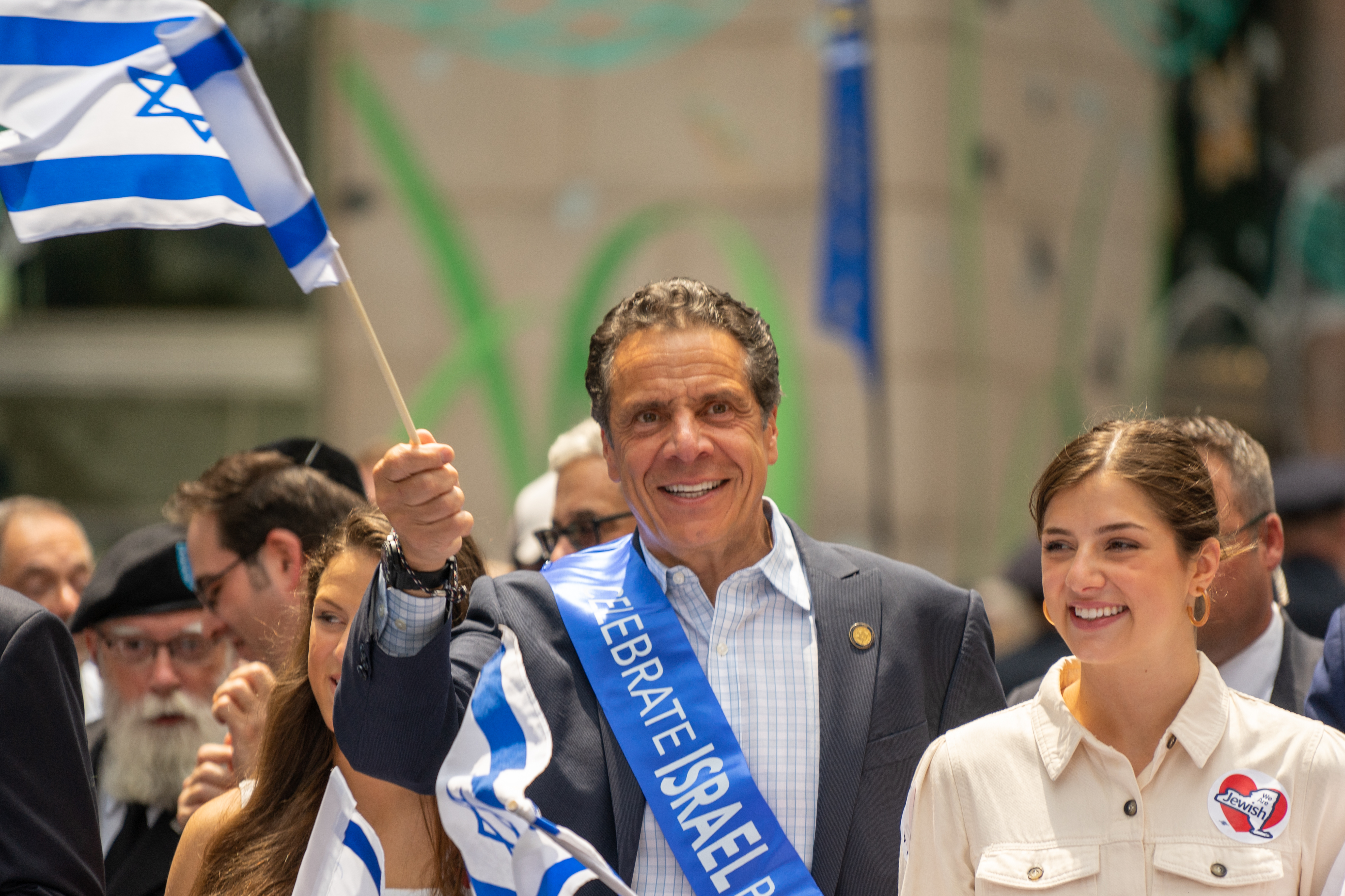 Former Gov. Andrew Cuomo in a "celebrate Israel" sash and holding an Israel flag