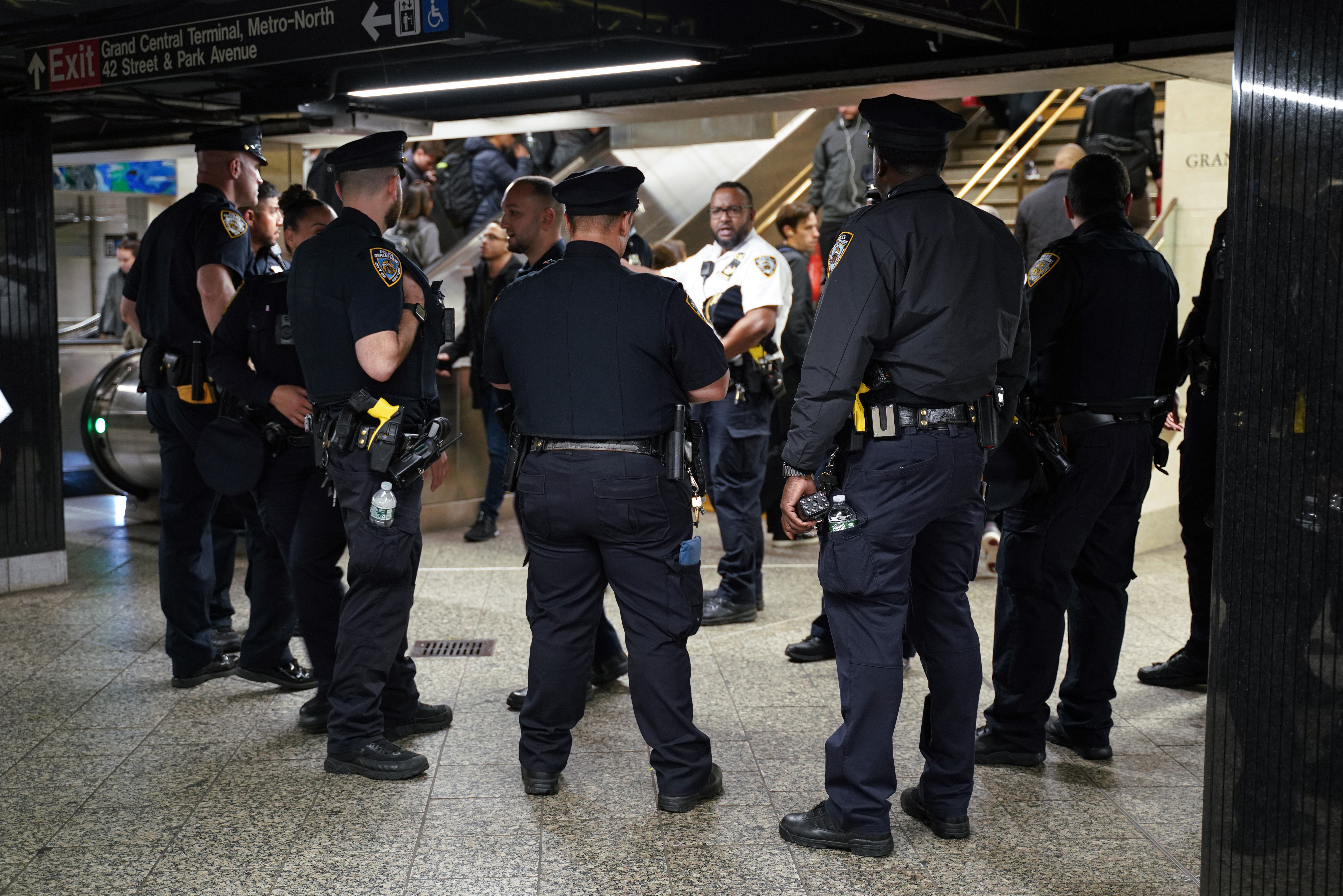 Police officers stand in a subway station.