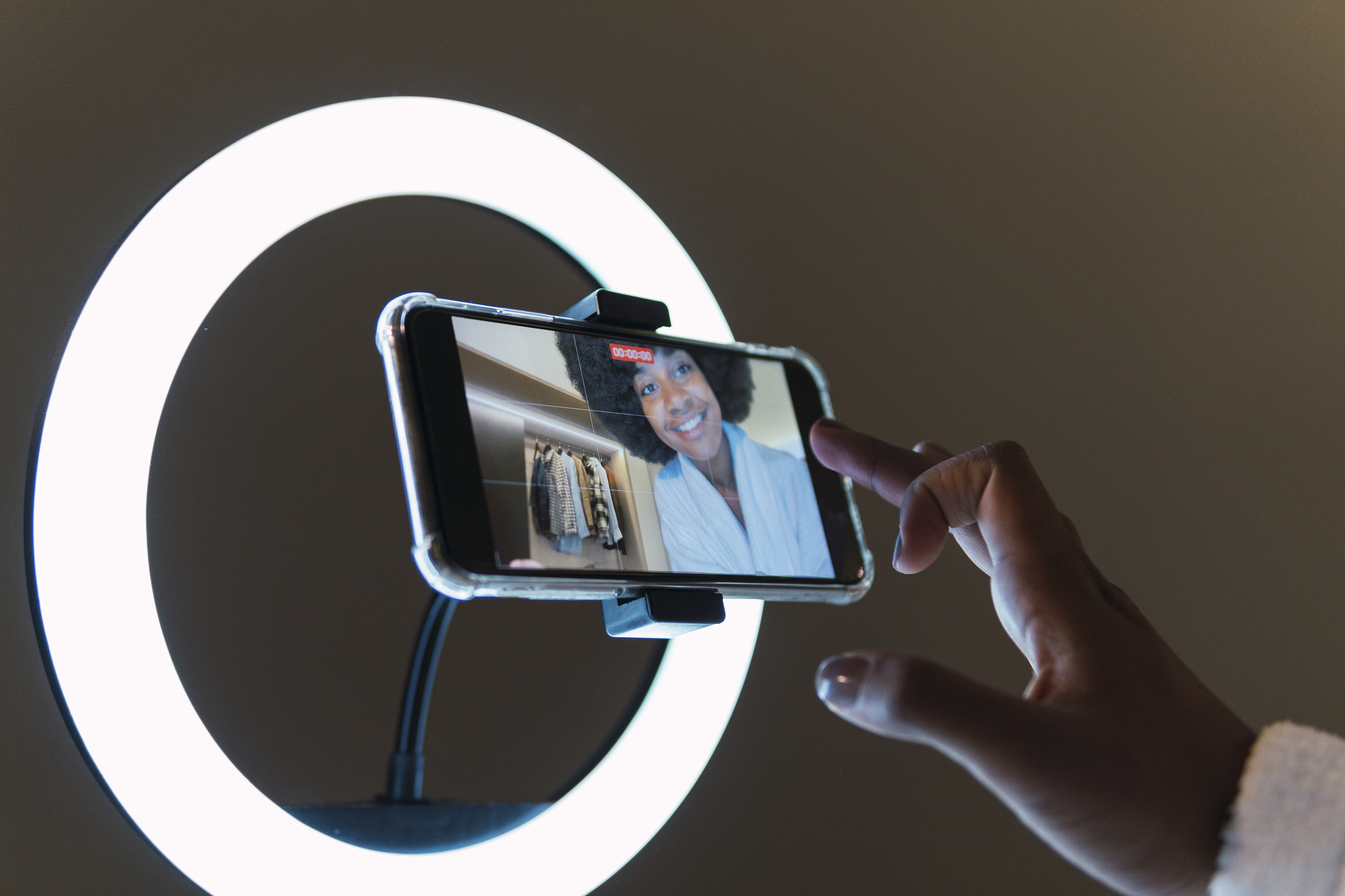 Woman recording herself on phone with ring lighting.