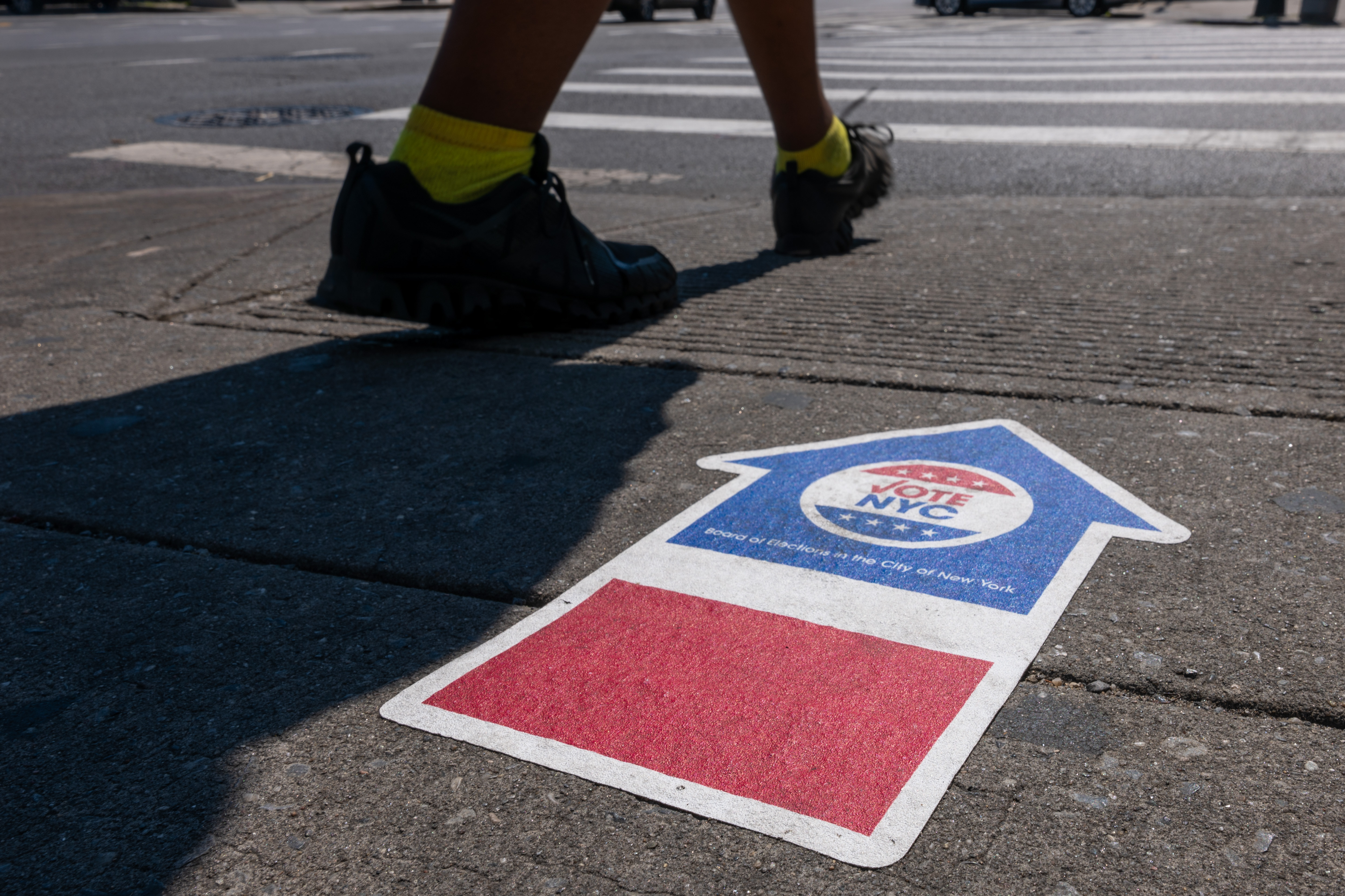 Feet walk on pavement with a vote here arrow