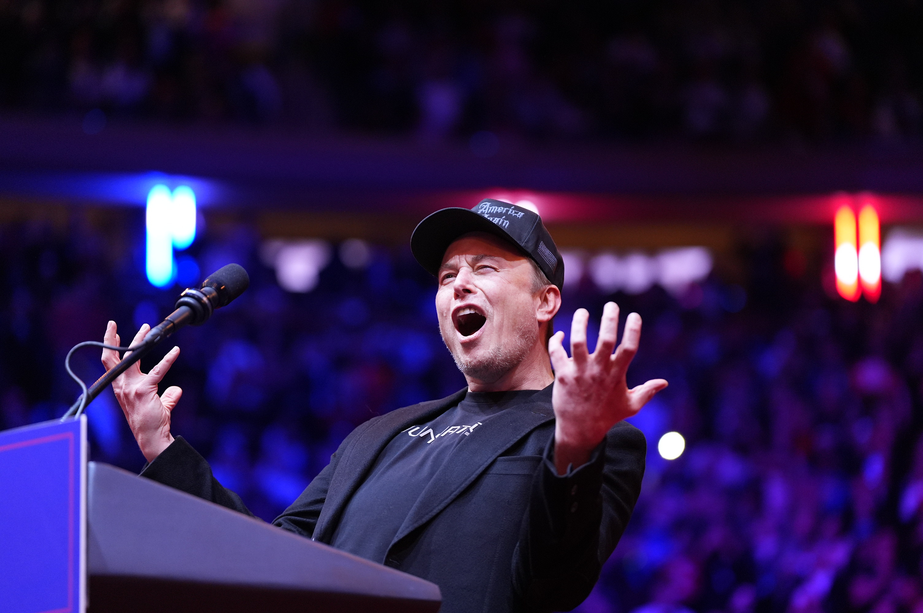 Elon Musk speaks at a podium.