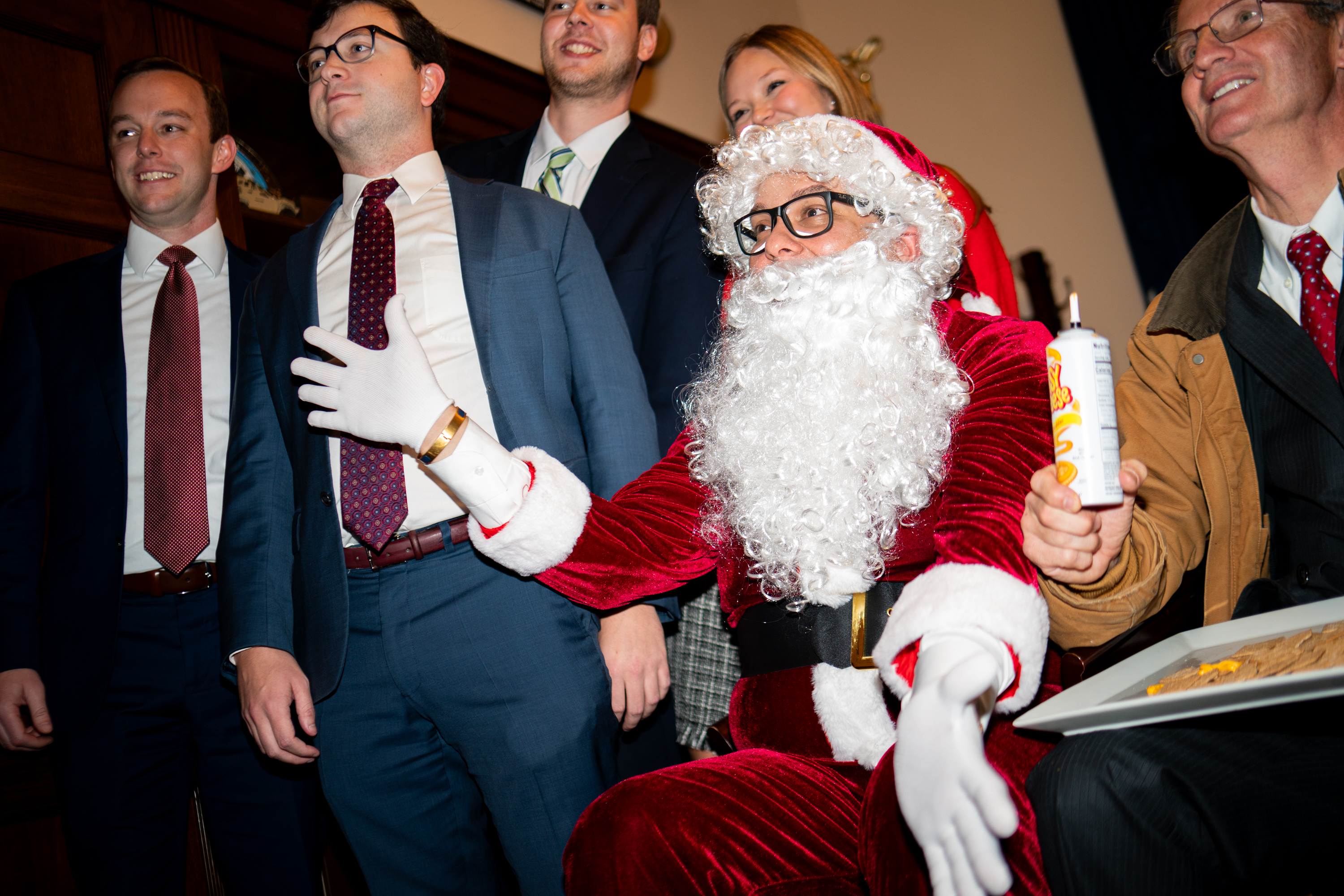 Former Republican Rep. George Santos in a Santa Claus costume with members of Congress and a can of spray cheese.