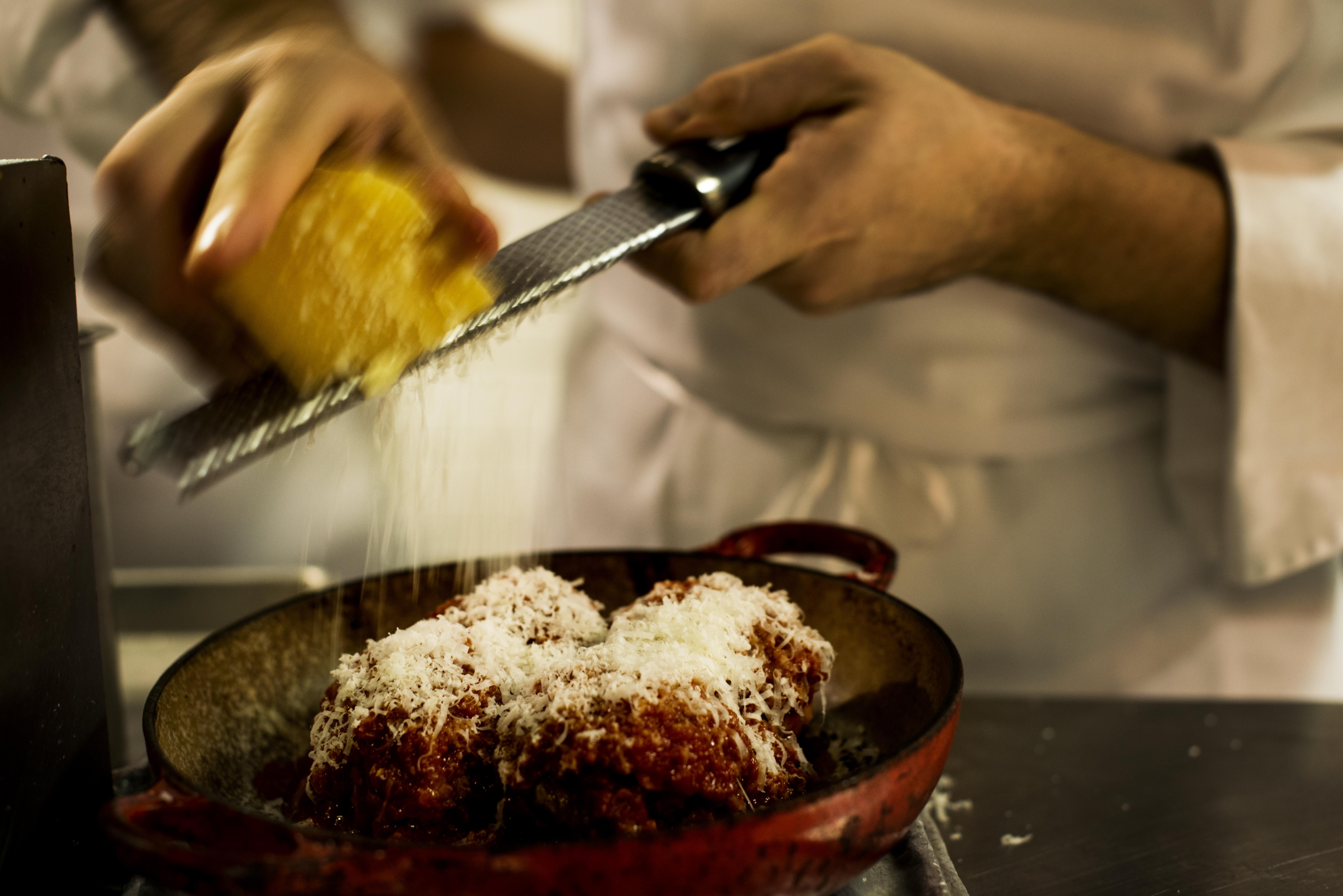 In the middle of busy dinner rush parmesan is graded onto meatballs at Carbone in Manhattan