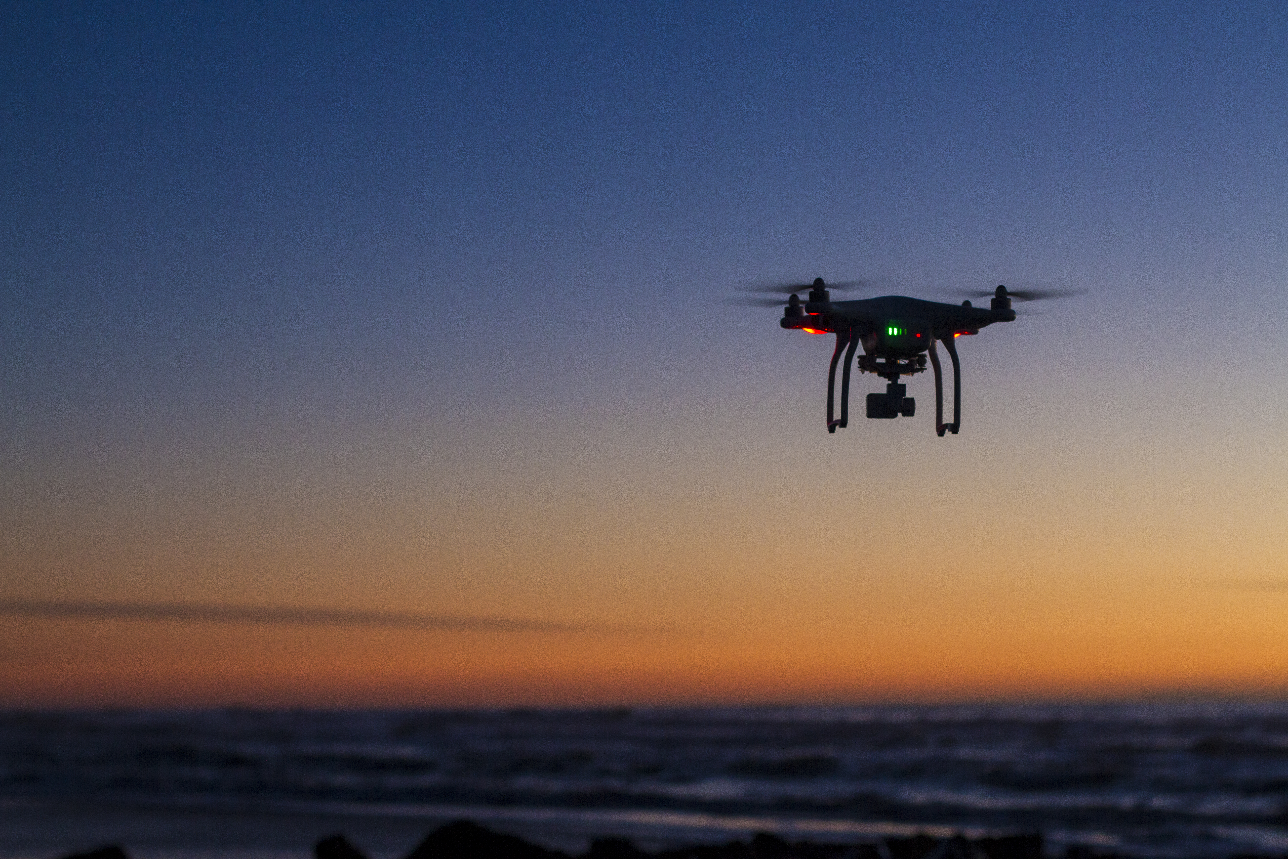 A drone flying over the ocean at dawn.