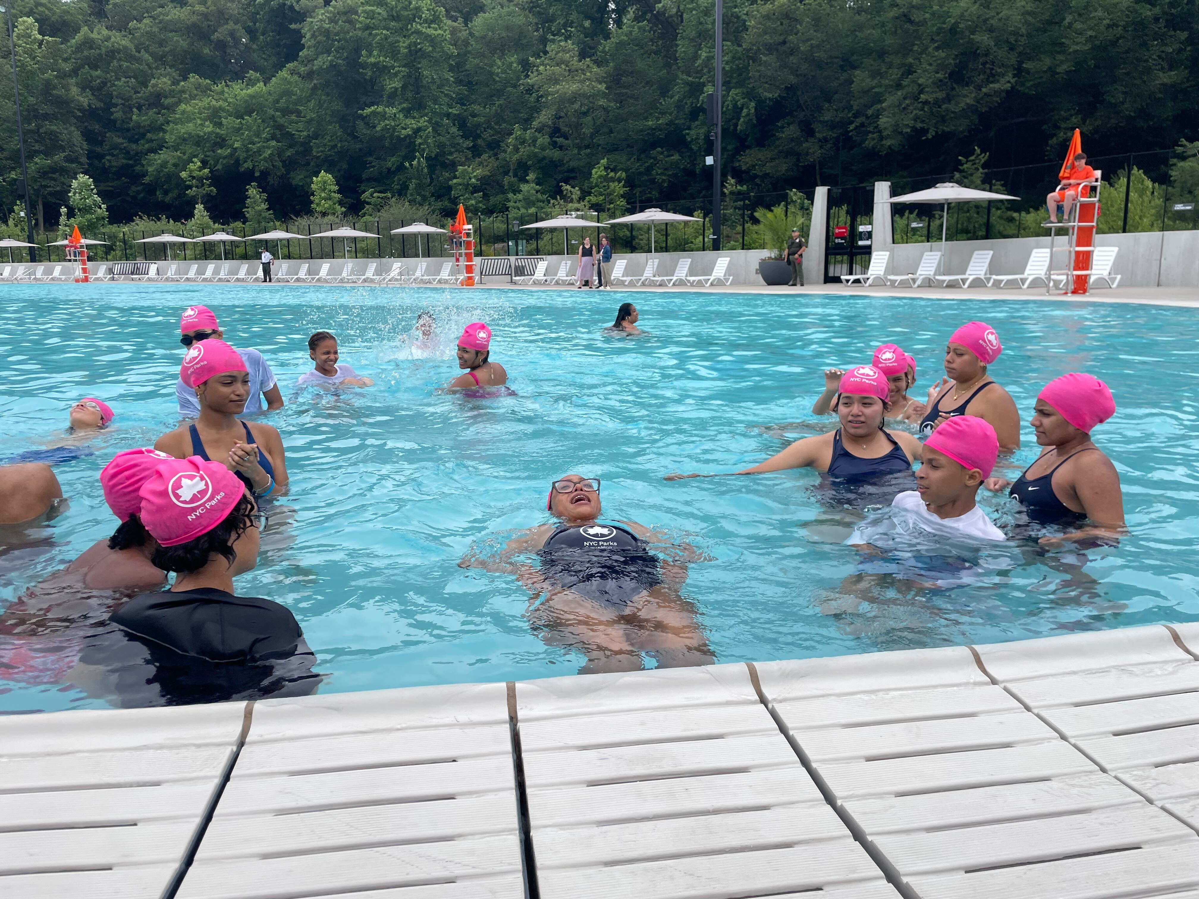 People of varying ages swim and play in a pool.