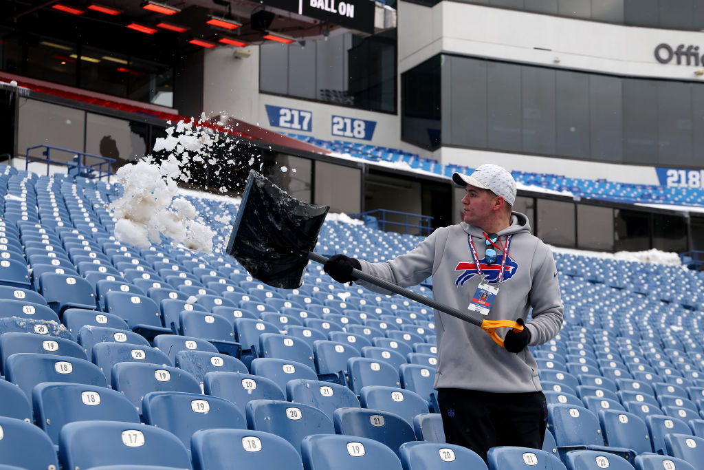 a guy with a shovel scooping snow in bills stadium