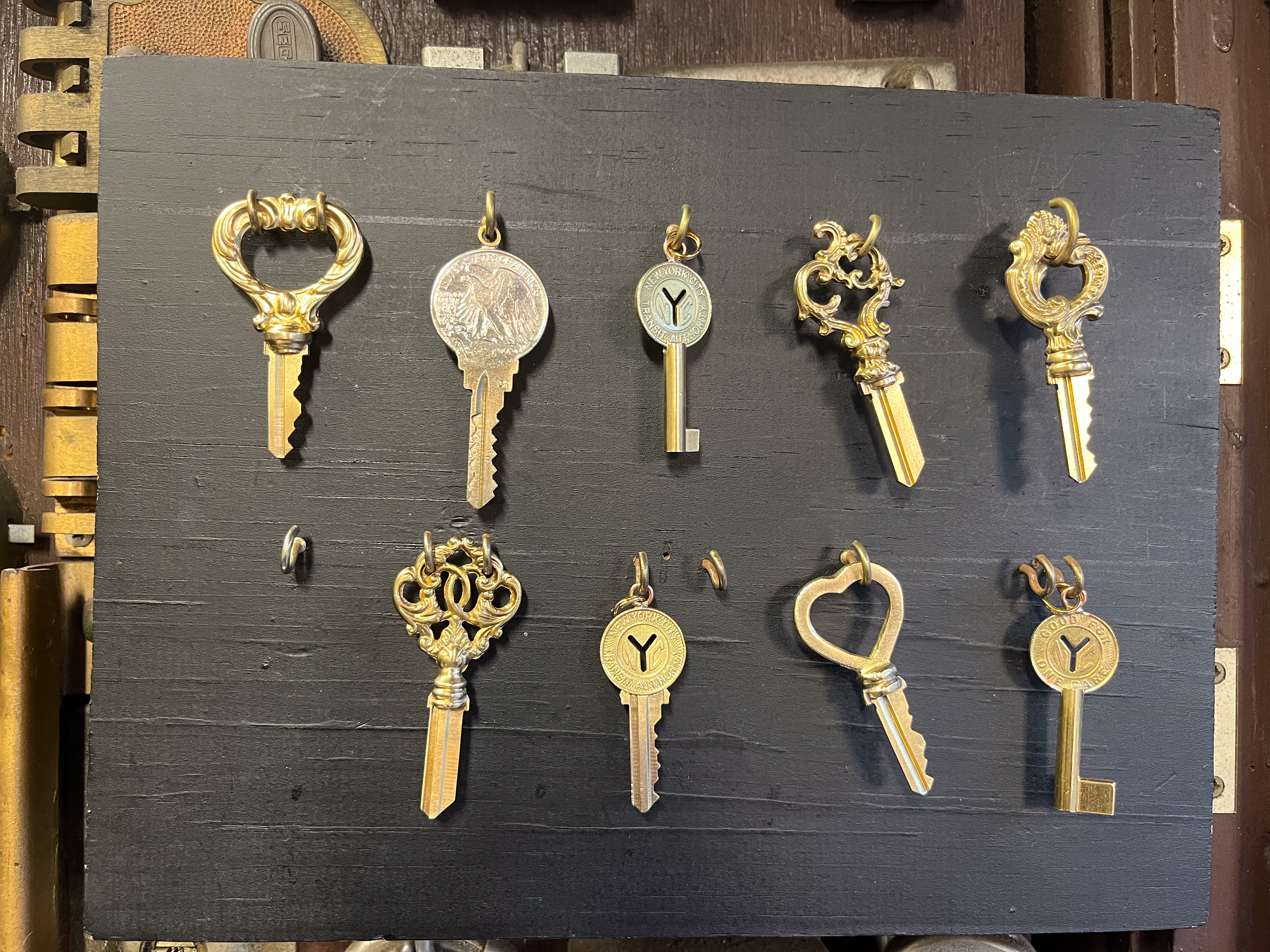 A series of gold and brass keys hanging on a board on a wall.