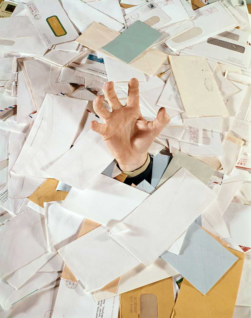 a hand sticking out of a pile of mail