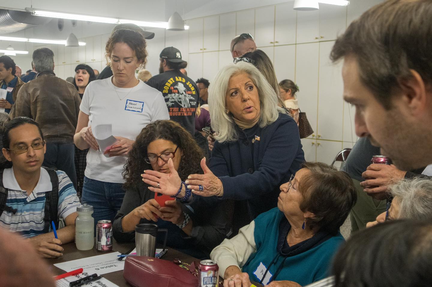 A councilmember speaks to people seated at a table.