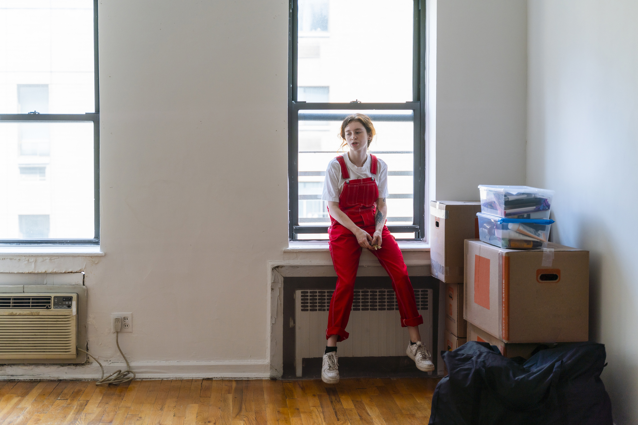 a woman in red overalls sit in her new apartment