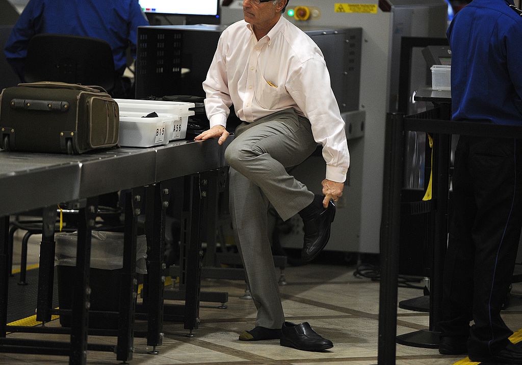a guy taking his shoes off at airport security